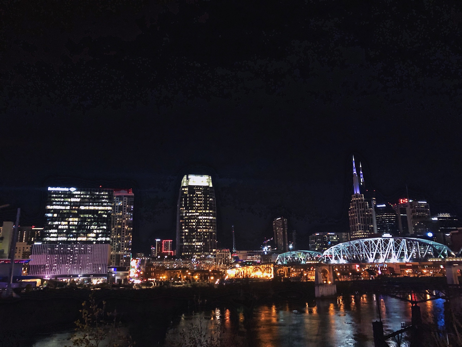 Nashville skyline and pedestrian bridge reflected in the river at night